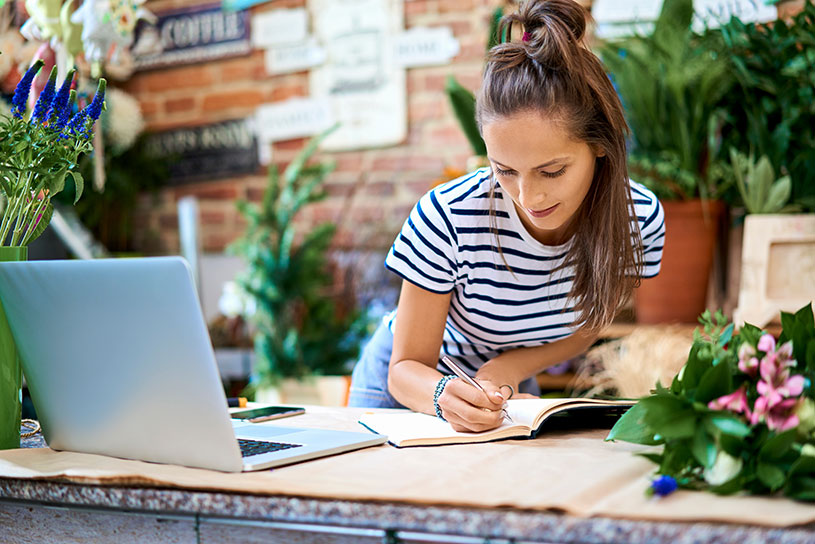 Flower shop owner writing in notebook