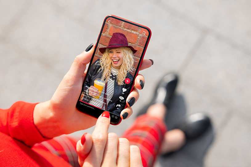 A woman watches an influencer on their mobile phone