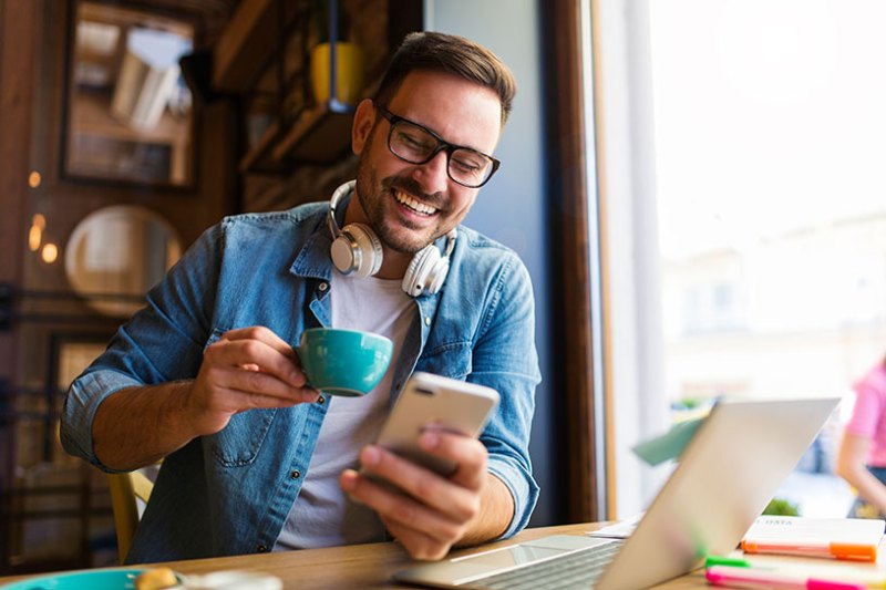 A man working on his phone while drinking coffee