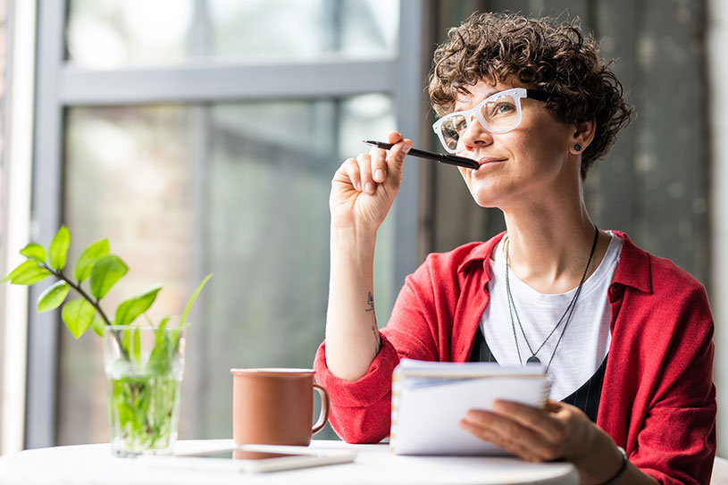 Creative woman thinking with a pen on her chin