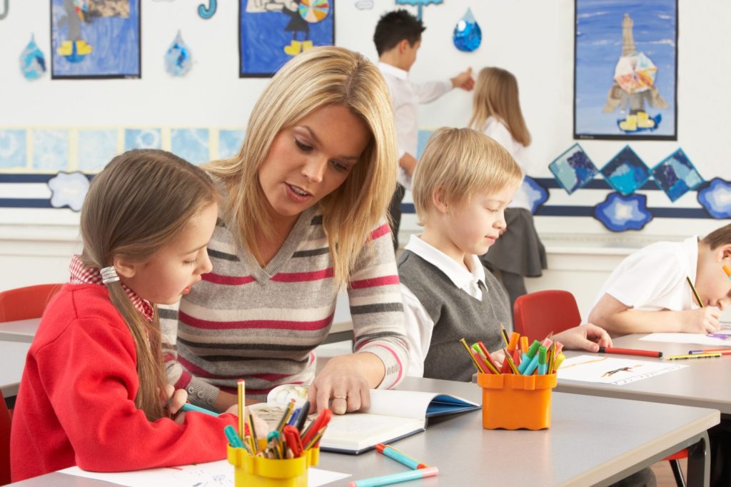 Teacher sits with classroom student