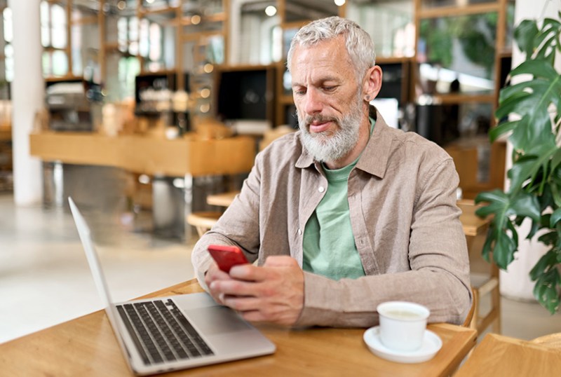 Landlord managing their property on their phone and laptop from a cafe