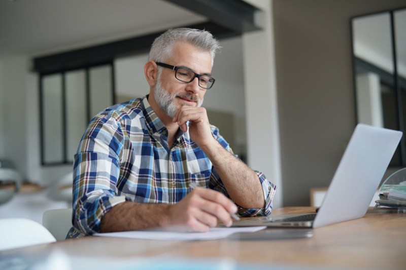 IT contractor working on paperwork and laptop.