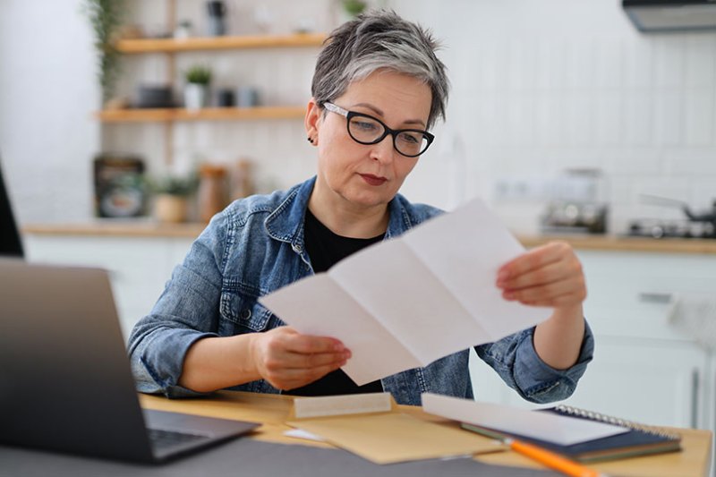 Women in glasses sorting invoices in kitchen