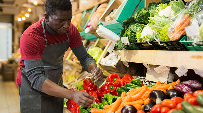 Greengrocer tidying vegetable display