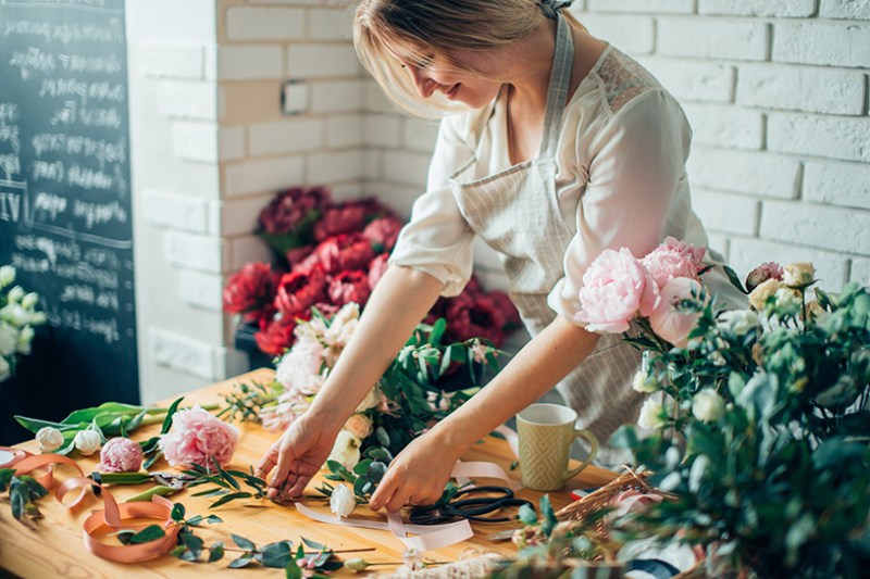 Smiling florist business owner arranging flowers