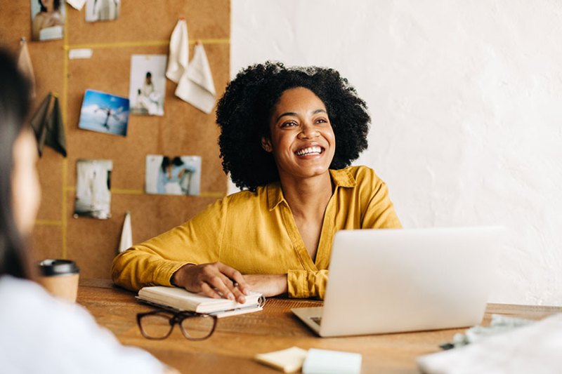 Smiling women with laptop and notepad