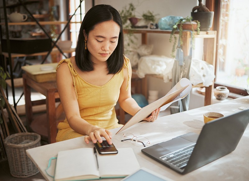 Woman working out finances with calculator and laptop