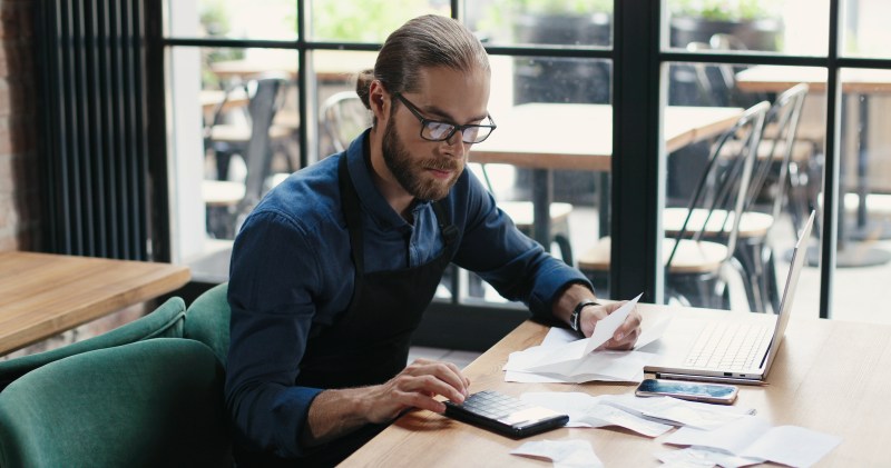 Man in glasses sitting at table and doing business calculations