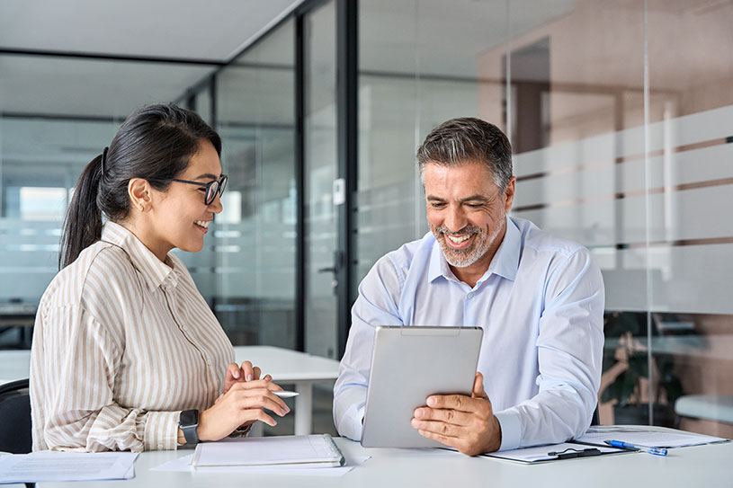 Two professionals speaking in office looking happy