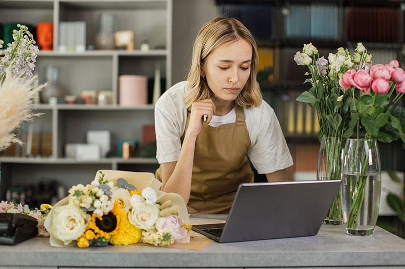 A small business owner reads business news on their laptop