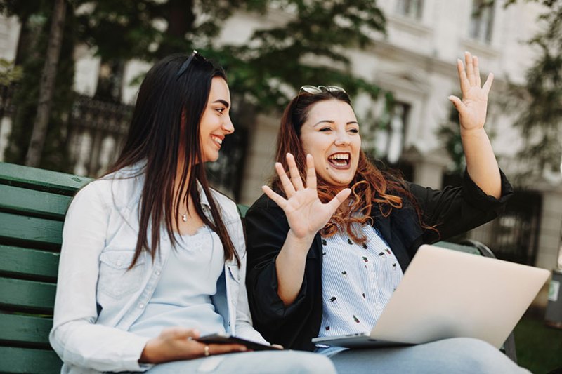 Two women working on a laptop whilst one of them tells a story