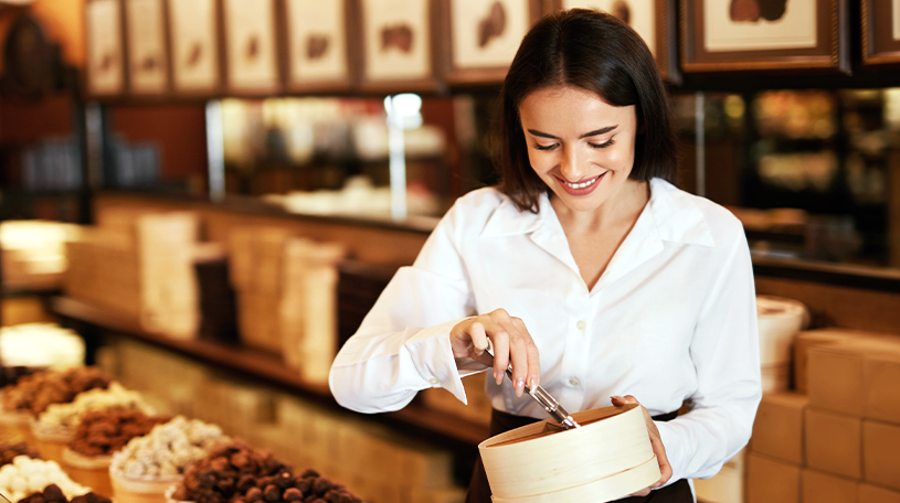 Female sweet shop worker scooping sweets into a paper bag