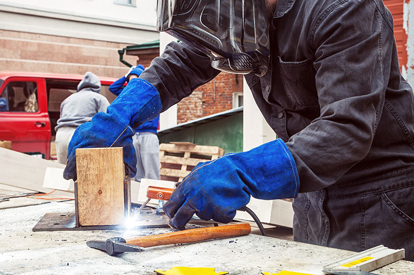 Man in welding mask welding with tools in the background