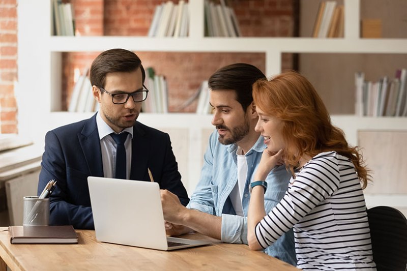 Two people with an estate agent signing tenancy agreement