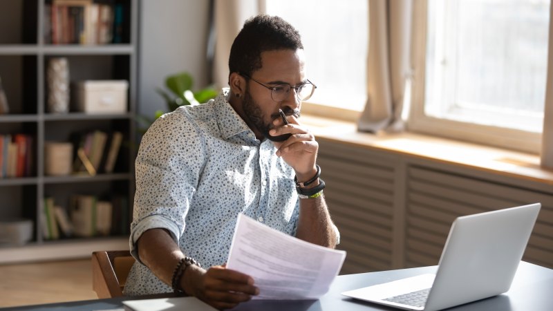 Man working on laptop with paperwork