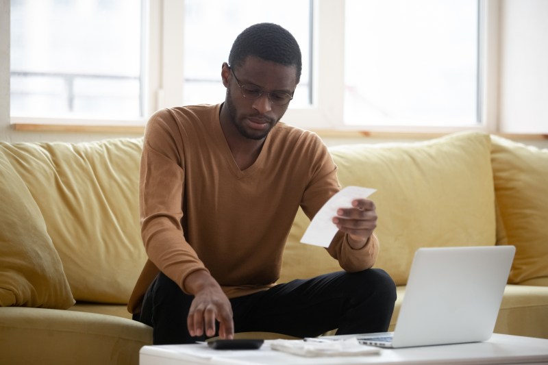 Man sat on sofa calculating expenses