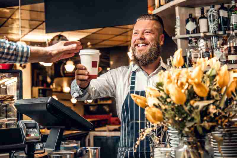 A man serving a takeaway coffee to a customer