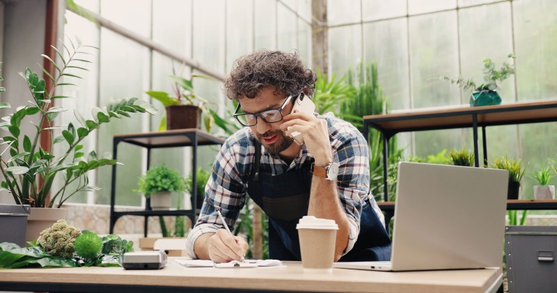 Smiling man in glasses talking on the phone in plant shop