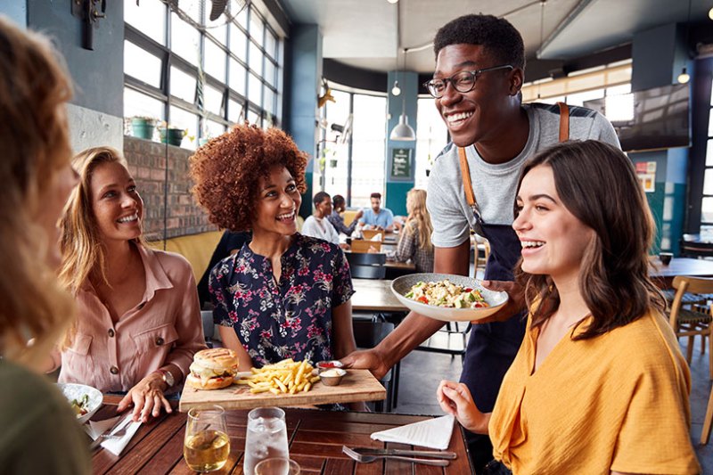 Waiter serving group of people in restaurant