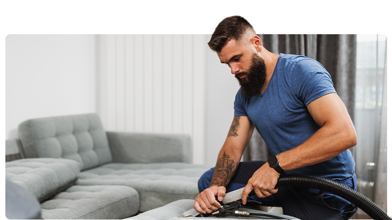 Carpet and upholstery clear - a man is cleaning a sofa with a professional ceaner