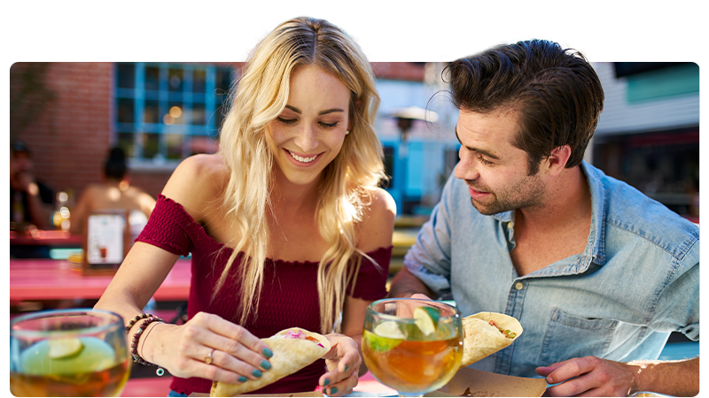 Food business: a woman and a man eating tacos and drinking cocktails