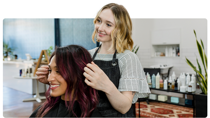 Two women in a hair salon with one styling the others hair