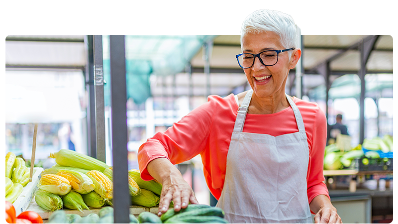 Woman market trader wearing an apron and organising vegetables