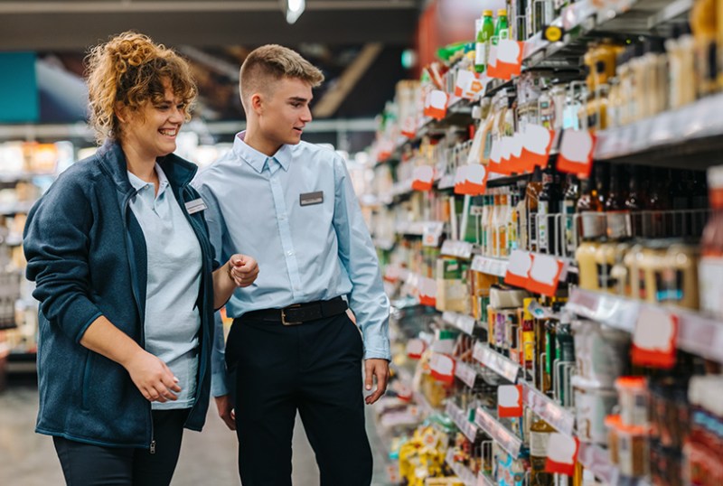 Employer and employee looking at shelves in shop