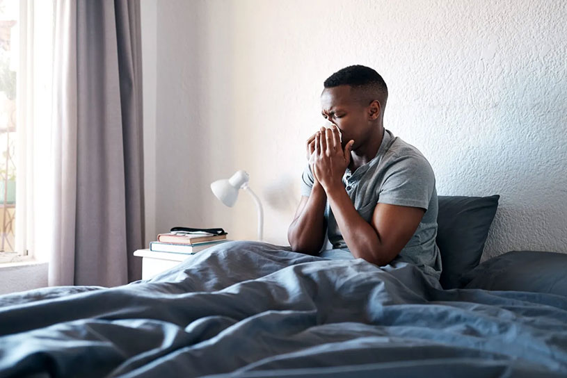 Self-employed man blows his nose in bed