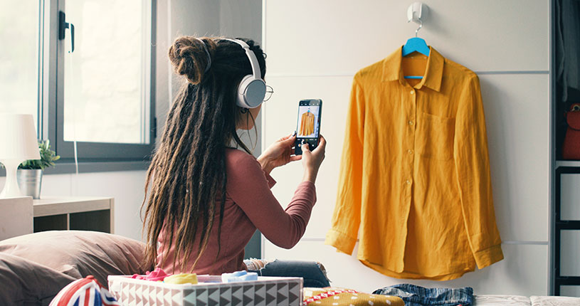 A woman takes a picture of a yellow shirt to sell online