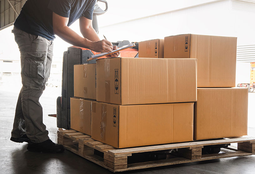 A man stacking cardboard boxes on a crate to become UK imports