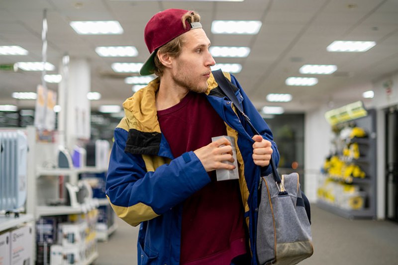 A male shoplifter puts an item under his coat