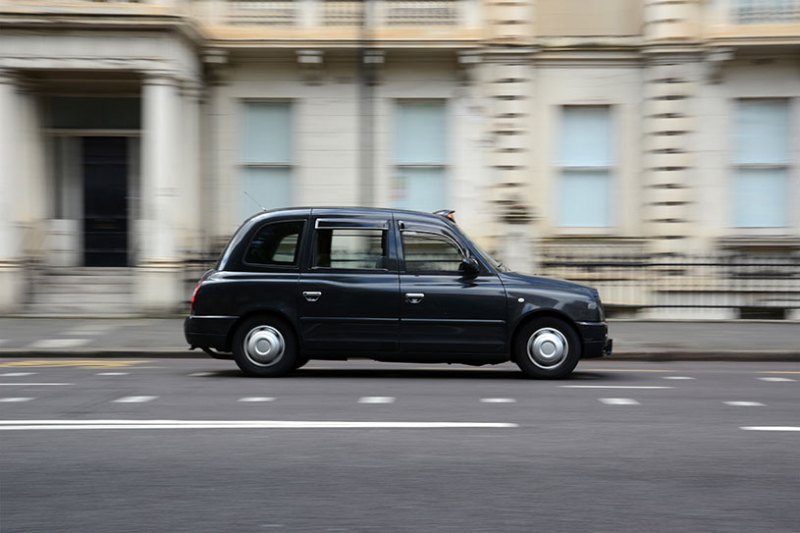 A black cab drives down a London street