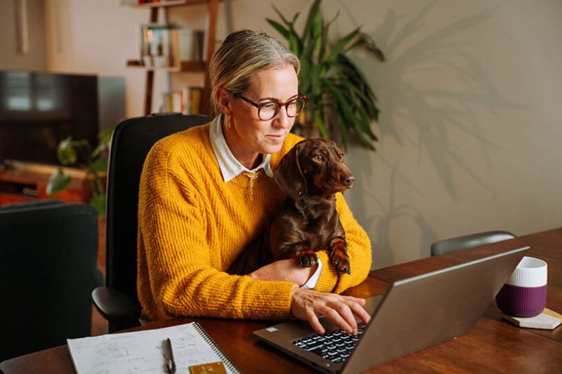 Contractor works from home on laptop with small dog